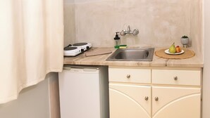Cocina compacta con lavamanos, un refrigerador pequeño y una encimera con una balanza y dispensador de jabón.