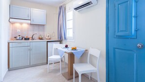 Una cocina compacta con armarios blancos, una mesa de comedor con dos sillas y una puerta azul.