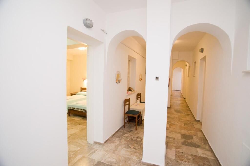A narrow hallway with arched doorways leading to a bedroom and a dining area.