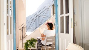 Una habitación con una cama, una silla, una maleta y una ventana que da a una escalera que lleva a un balcón.