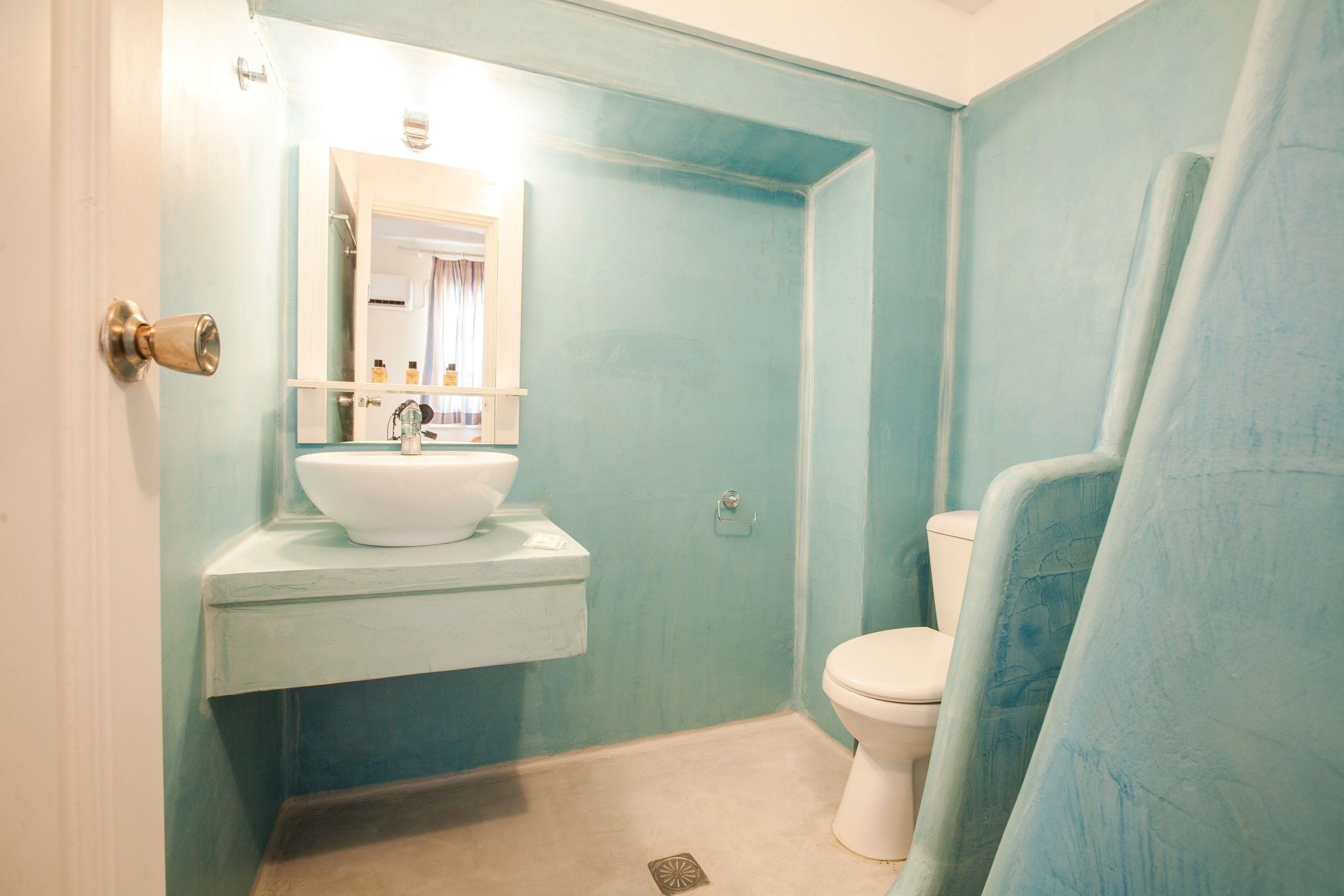 A bathroom with a sink, mirror, toilet, and shower curtain.
