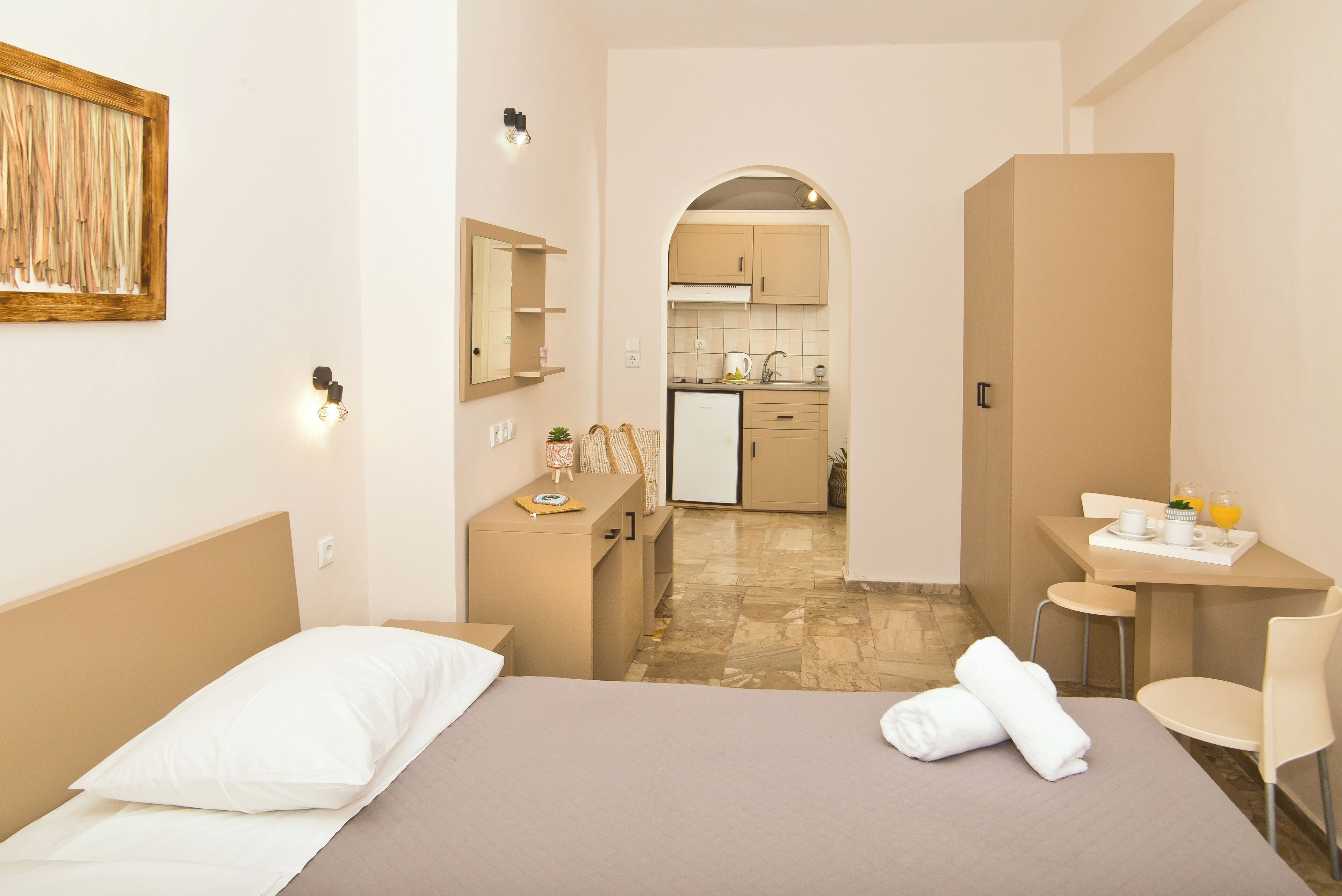 Een hotelkamer met een bed, een bureau, een stoel, een kleine kitchenette en een badkamer.