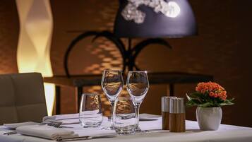 A table set with three wine glasses, a vase with flowers, and salt and pepper shakers.