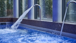 A hot tub with a water spout, surrounded by a tiled area and large windows. - Mercure Bale Mulhouse Aeroport (Blotzheim)