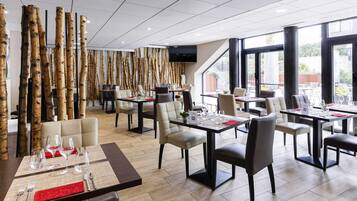 A modern restaurant with high tables and chairs, a wooden wall feature, and large windows offering a view.