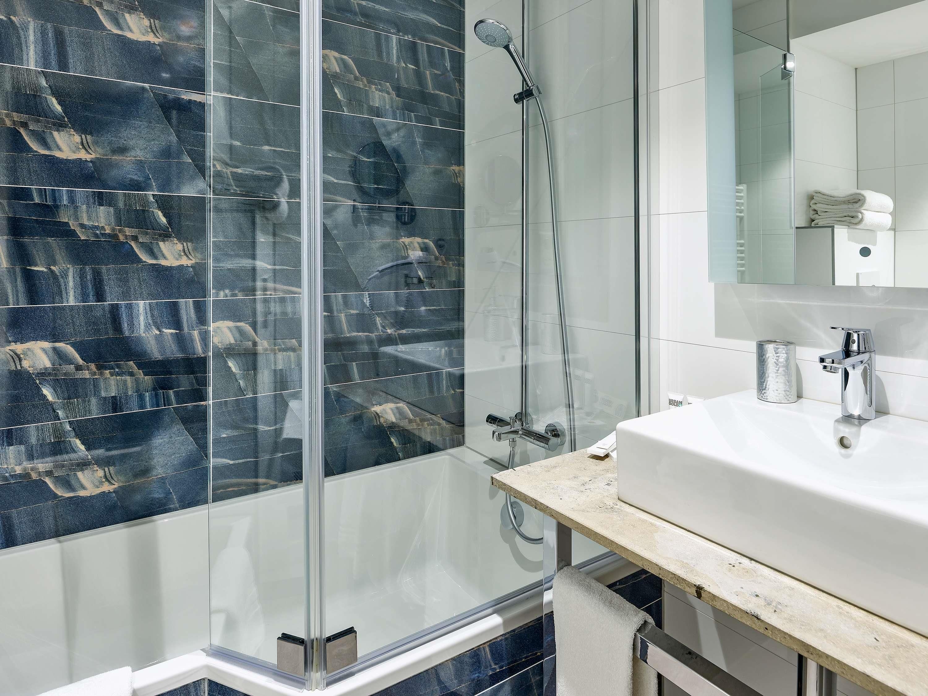 Une salle de bain moderne avec une douche à parois de verre, un lavabo blanc et un miroir au-dessus.