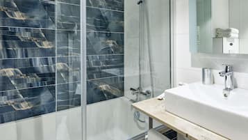 Une salle de bain moderne avec une douche à parois de verre, un lavabo blanc et un miroir au-dessus.