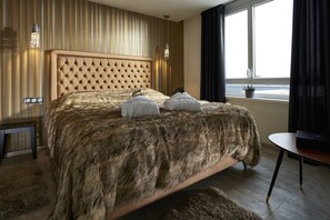 A bedroom with a tufted headboard, a fur-covered bed, a bedside table, and a window with curtains. - Mercure Bale Mulhouse Aeroport (Blotzheim)