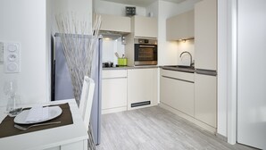 Una cocina moderna con armarios blancos, horno integrado y un lavamanos.
