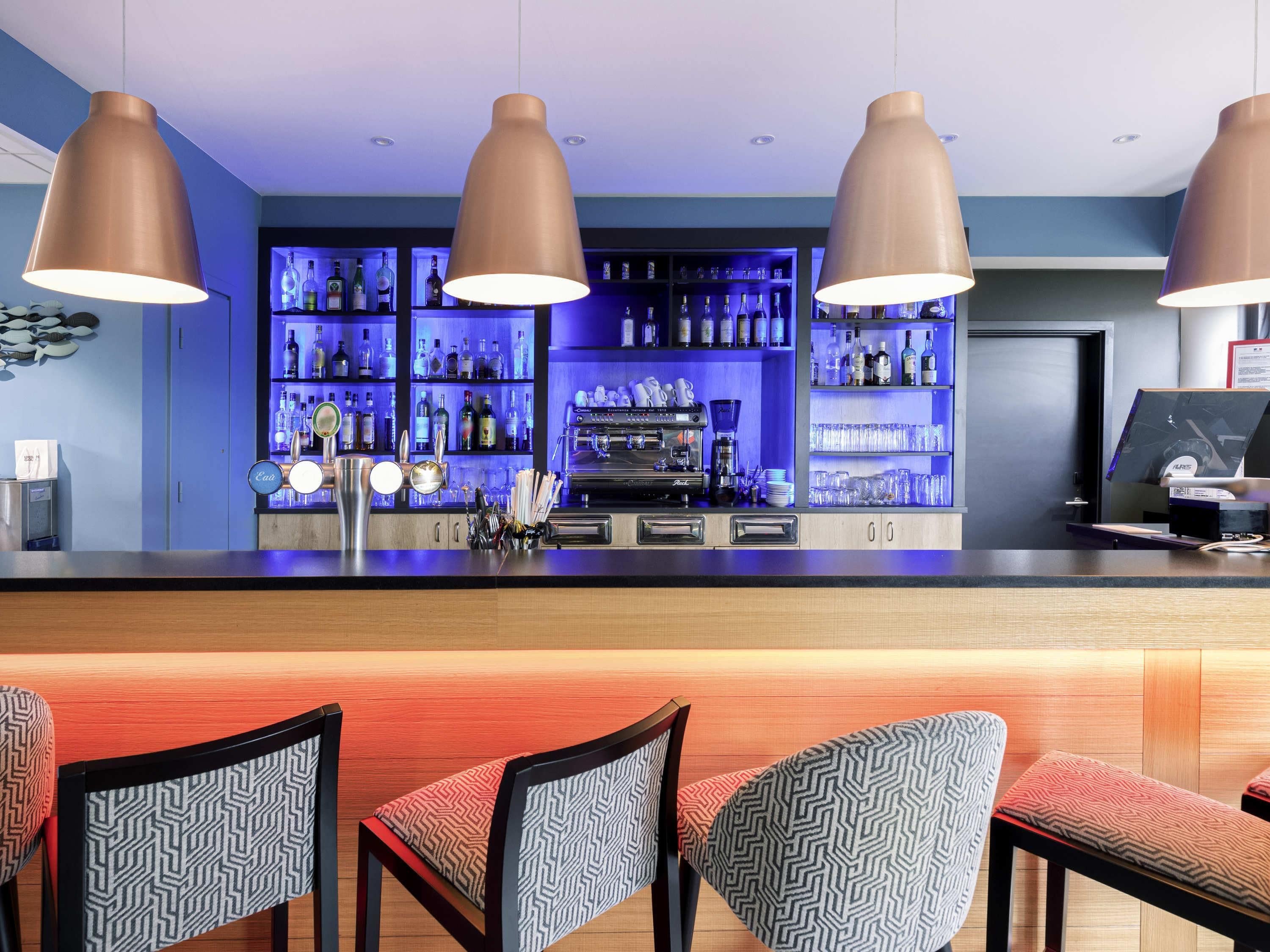 Eine Bar mit einer Theke, verschiedenen Sitzgelegenheiten und einem gut sortierten Regal voller Flaschen.