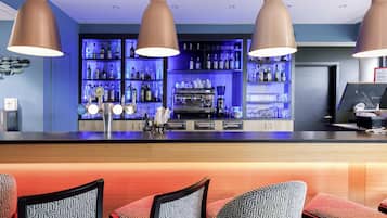 Eine Bar mit einer Theke, verschiedenen Sitzgelegenheiten und einem gut sortierten Regal voller Flaschen.