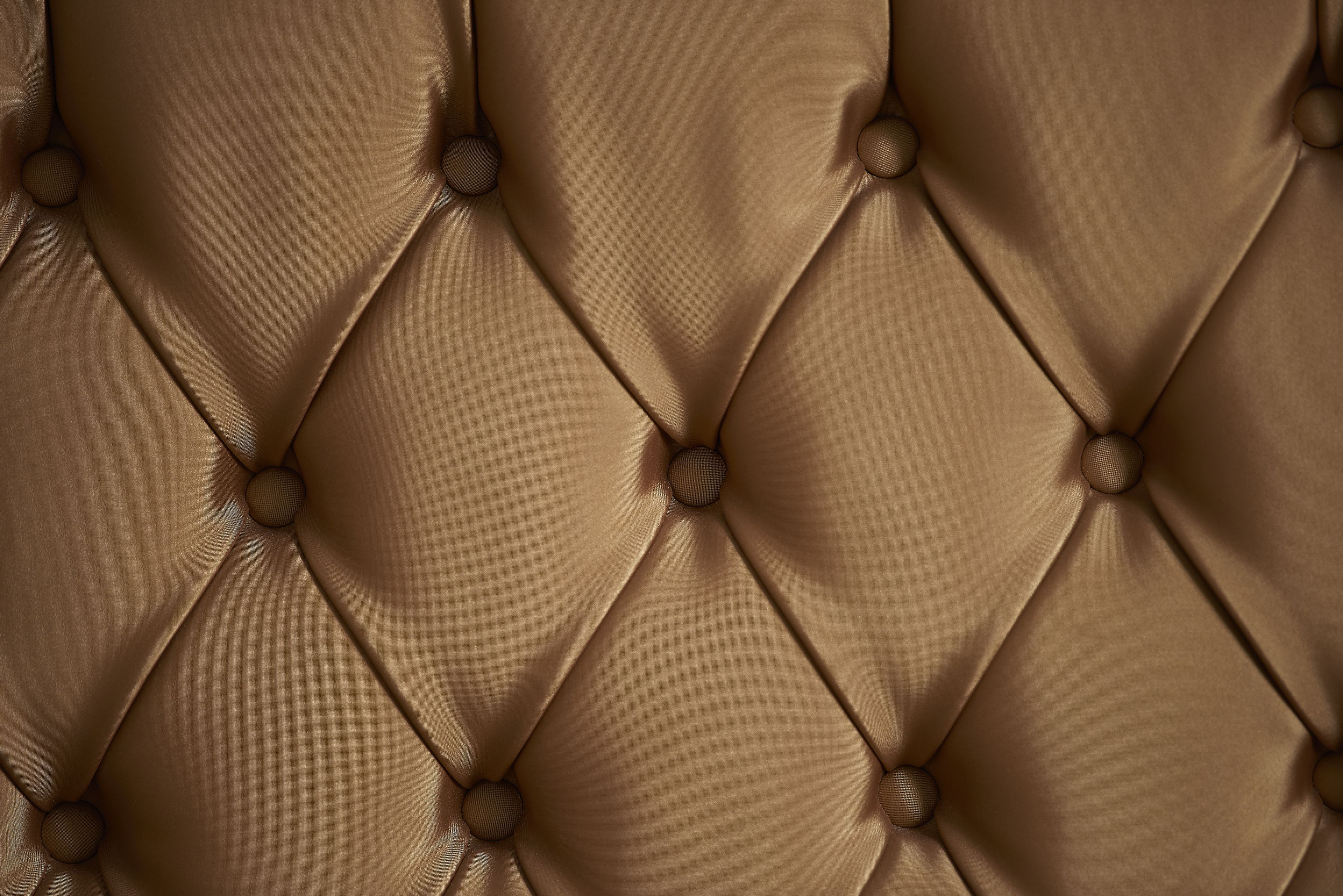 A close-up of a tufted leather headboard with round buttons.