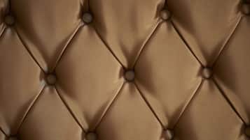 A close-up of a tufted leather headboard with round buttons.