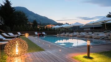 Una piscina techada, una piscina al aire libre, sombrillas