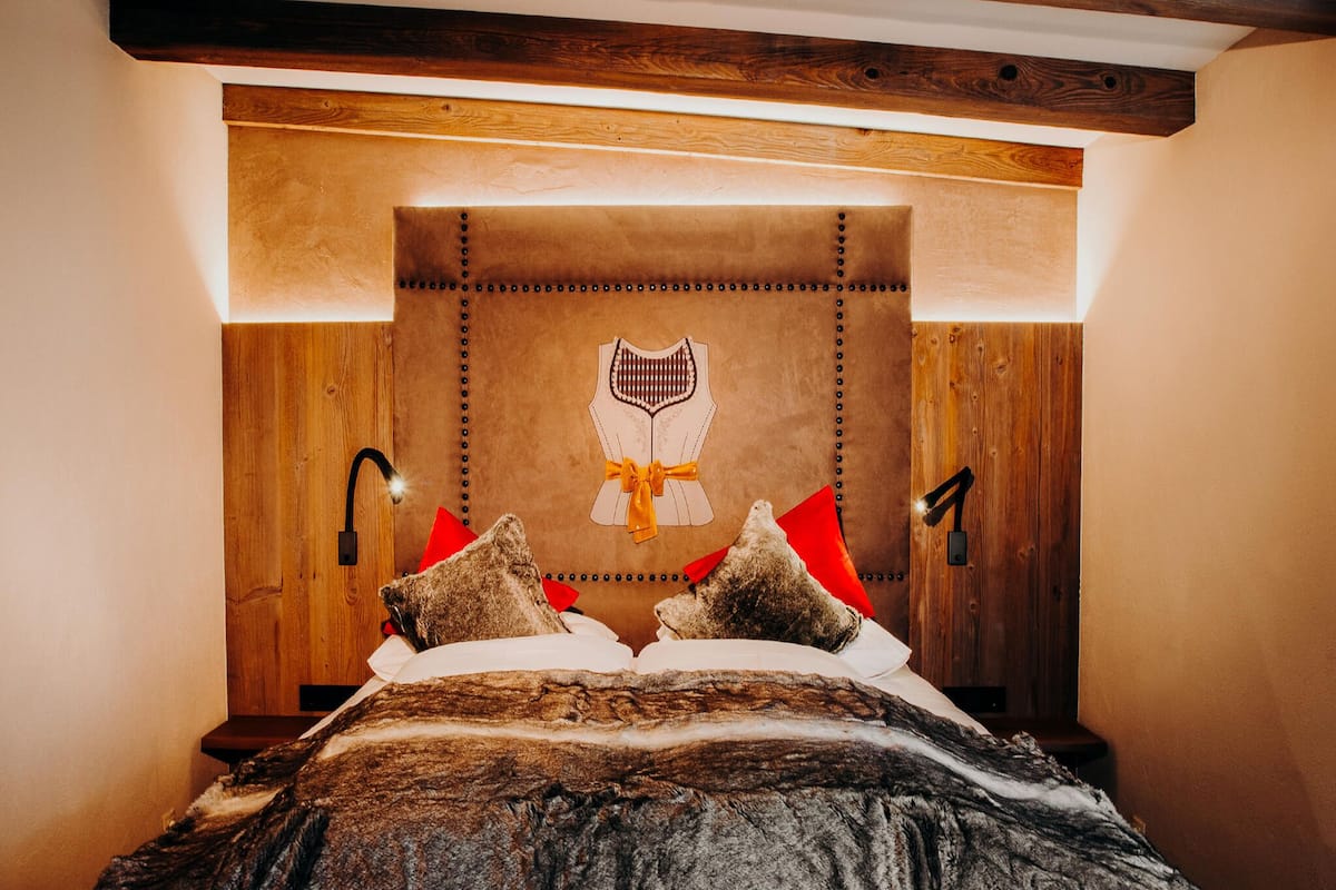 Ein Schlafzimmer mit einem hölzernen Kopfteil, einem Bett mit gemustertem Überwurf und zwei roten Kissen.