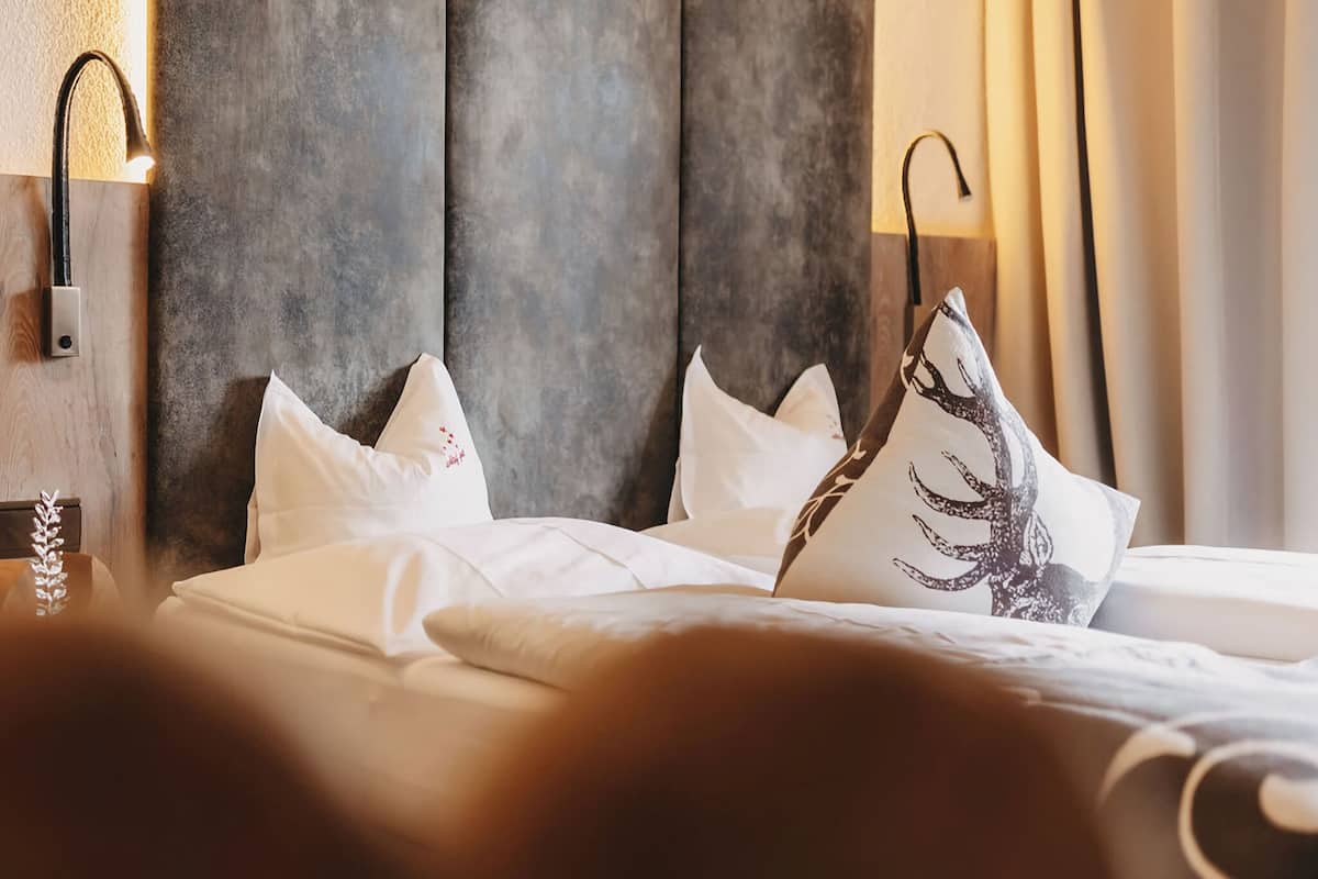 Ein Hotelzimmer mit einem großen Bett, zwei Nachttischlampen und einem strukturierten Kopfteil.