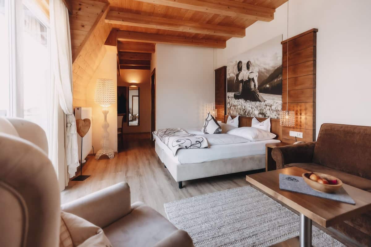 Ein Schlafzimmer mit Bett, Nachttisch, Holz-Kopfteil, Schreibtisch und Stuhl.
