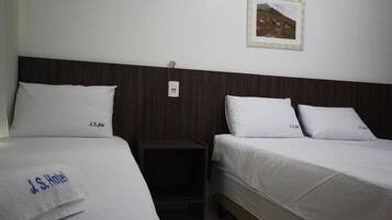 Habitación de hotel con dos camas, cada una con ropa blanca y almohadas con el logo de "J.S. Hotel".