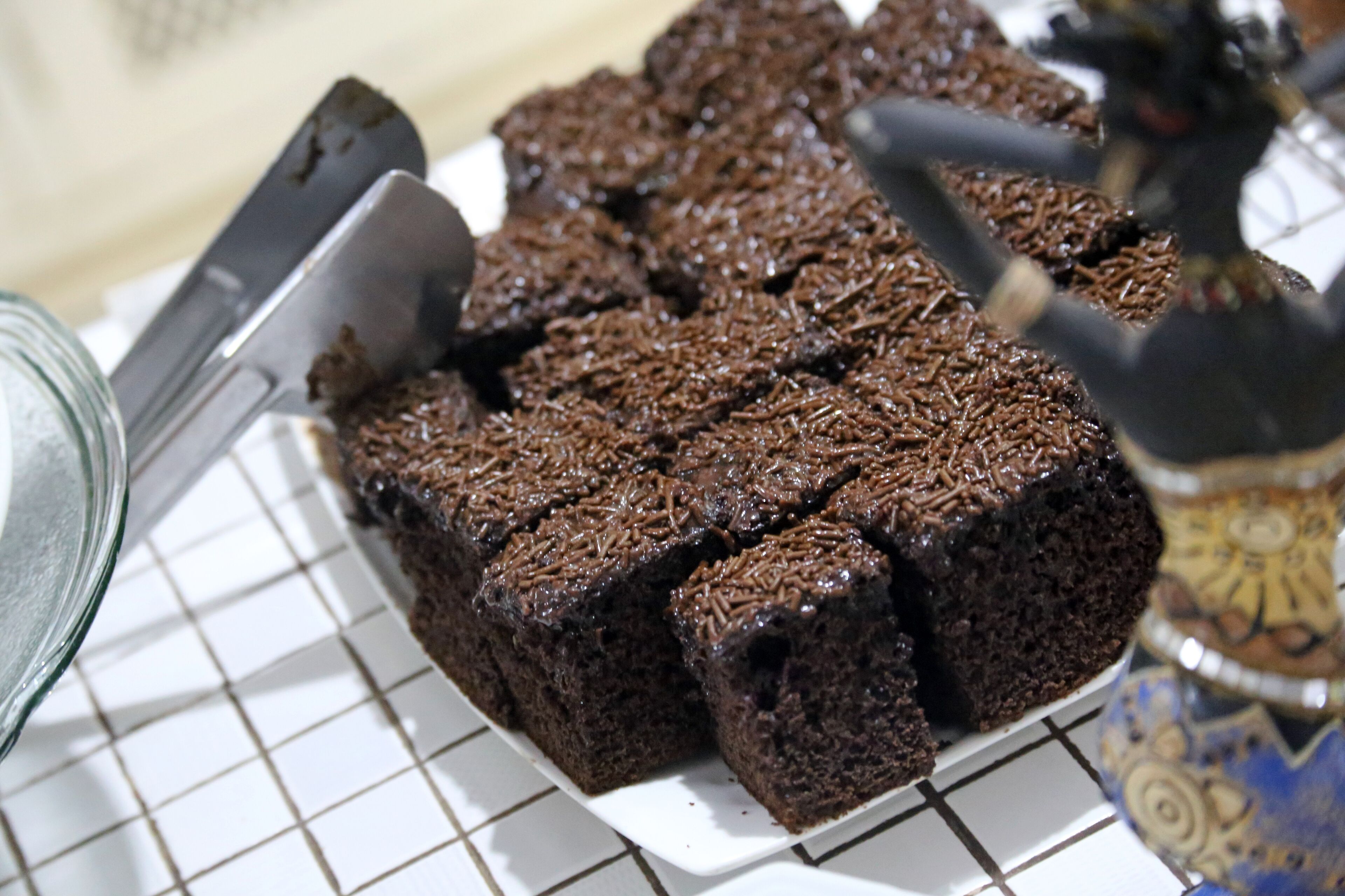 Uma travessa de brownies sobre um prato branco com padrão quadriculado.