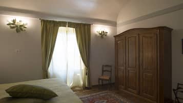 Ein Schlafzimmer mit einem Bett, einem Holzschrank, einem Sessel und einem gemusterten Teppich.
