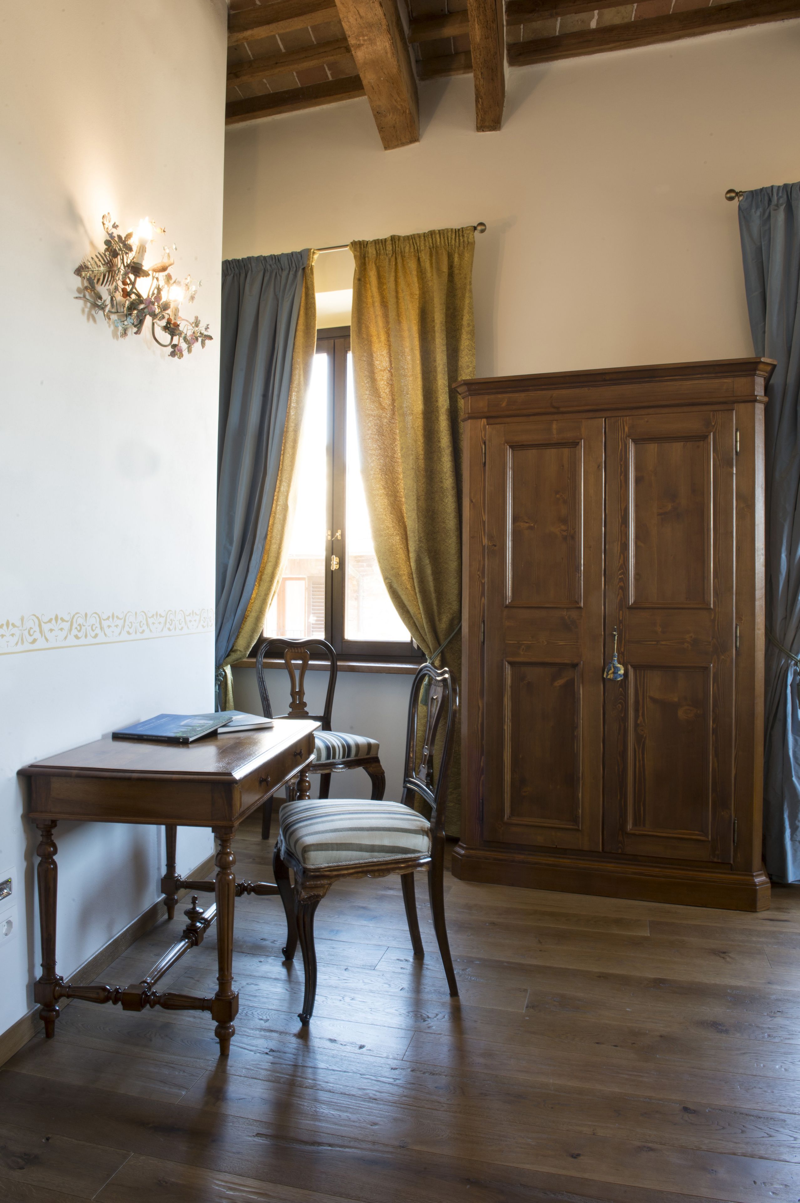 A room with a wooden desk, chair, and wardrobe.