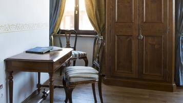 A room with a wooden desk, chair, and wardrobe.
