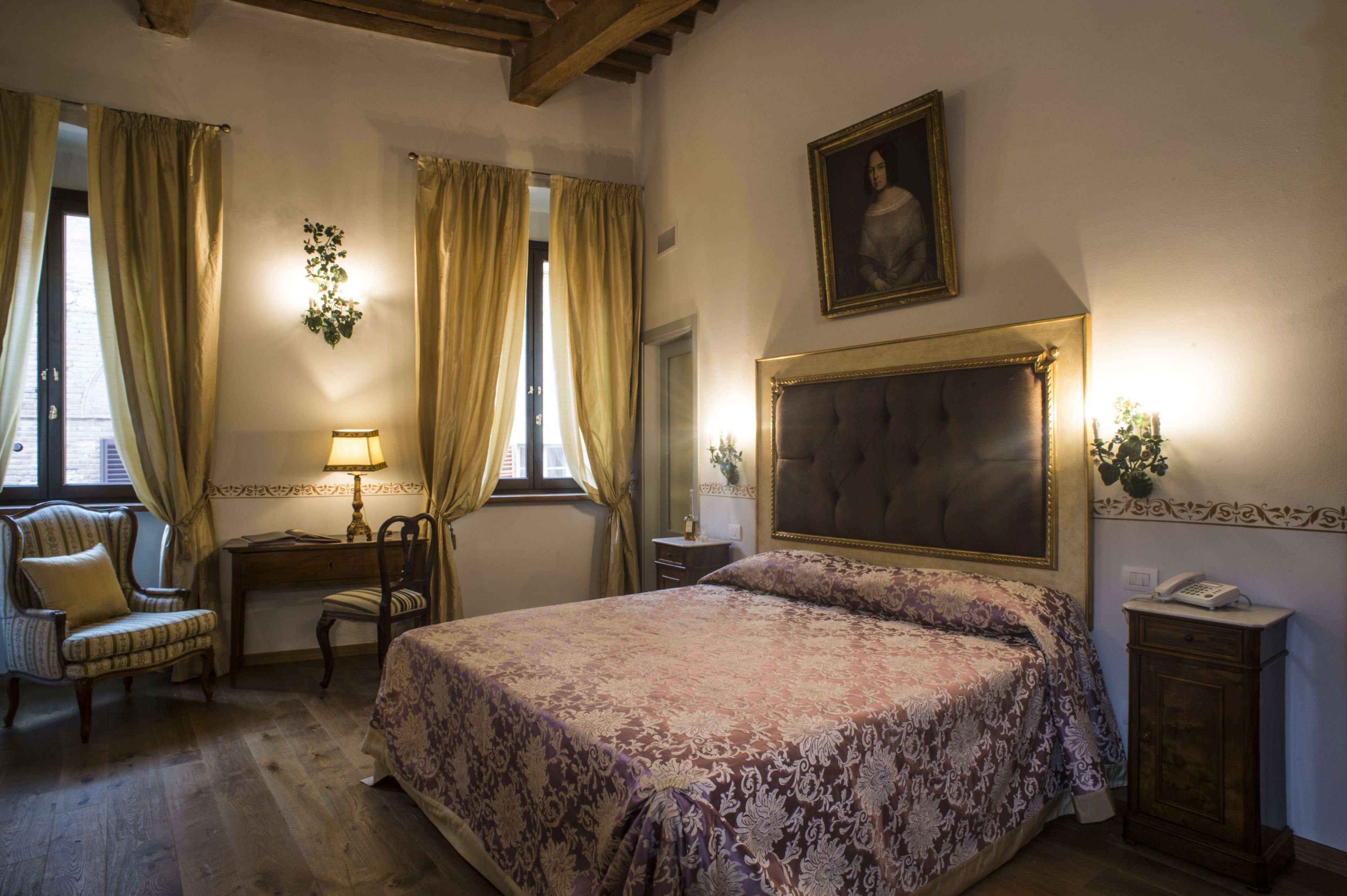 A bedroom with a large bed, a chair, a desk, and a nightstand.