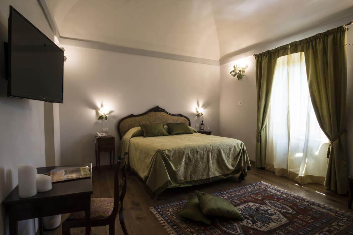 Un dormitorio con cama, mesitas de noche, televisor de pantalla plana y ventana con cortinas.