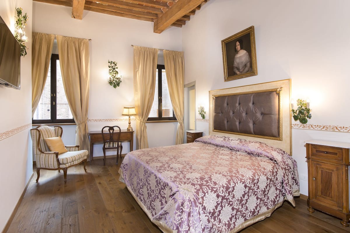 Un dormitorio con una cama grande, un escritorio de madera, una silla y un armario.