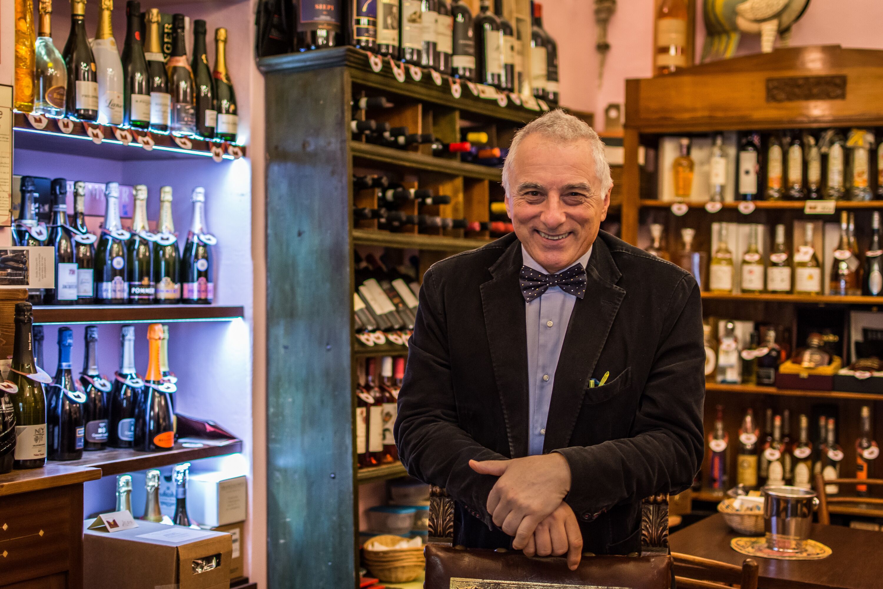 Eine Bar mit Regalen voller Flaschen und ein Mann, der hinter der Theke steht.