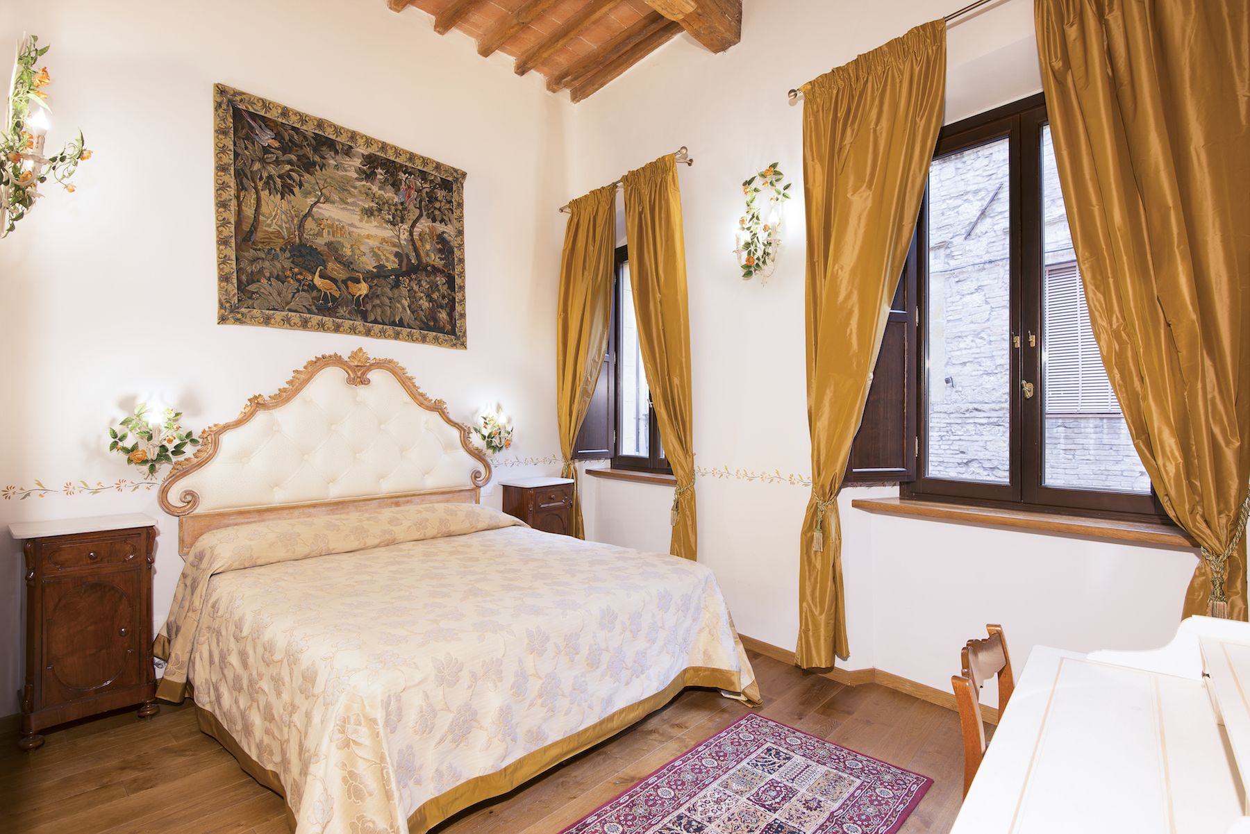 Une chambre à coucher avec un grand lit, une tête de lit en bois, un tableau au mur et une fenêtre avec des rideaux.