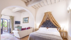 A bedroom with a large bed, a sofa, a television, and a painting on the wall. - Palazzo Pacini (Colle di Val d'Elsa)