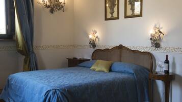 A bedroom with a bed, a nightstand, a wall-mounted lamp, and a framed picture.