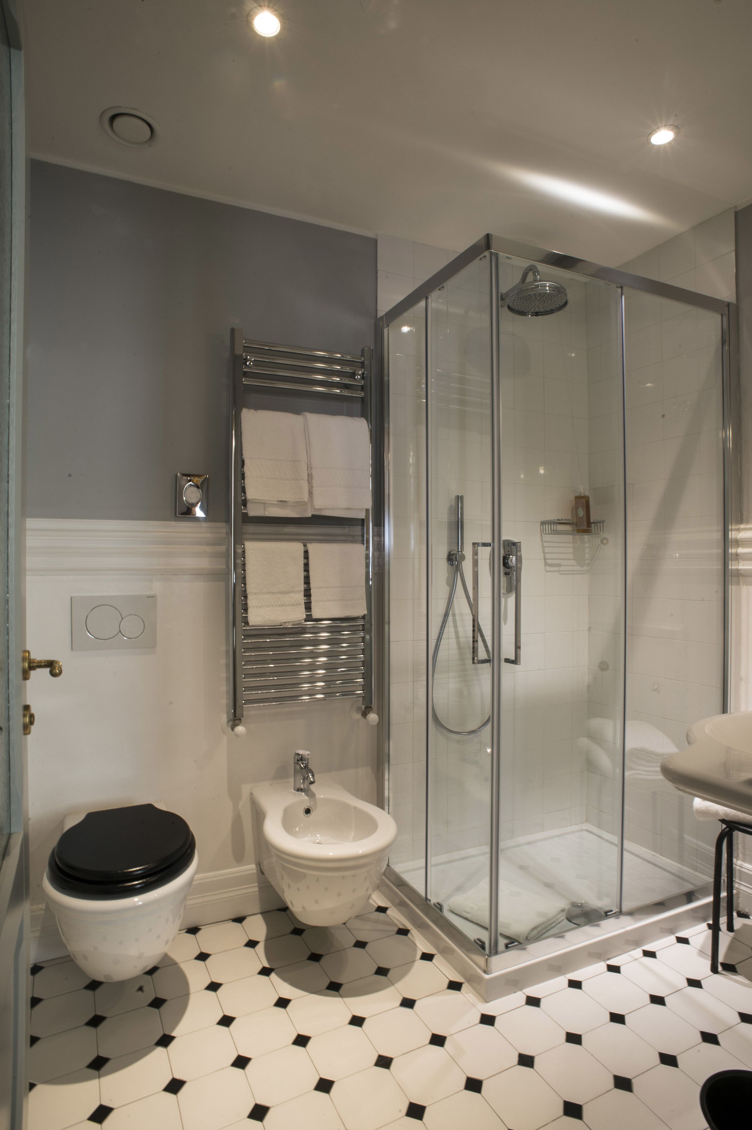 A modern bathroom with a glass-enclosed shower, a white toilet, and a bidet.