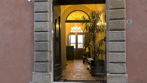 An arched entrance to a building with a tiled floor and a staircase leading inside. - Palazzo Pacini (Colle di Val d'Elsa)
