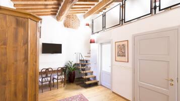 A wooden staircase with a red accent wall, a flat-screen TV, and a door with a framed picture.