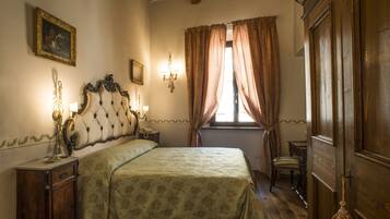 A bedroom with a large bed, a nightstand, a dresser, a chair, and a window with curtains.