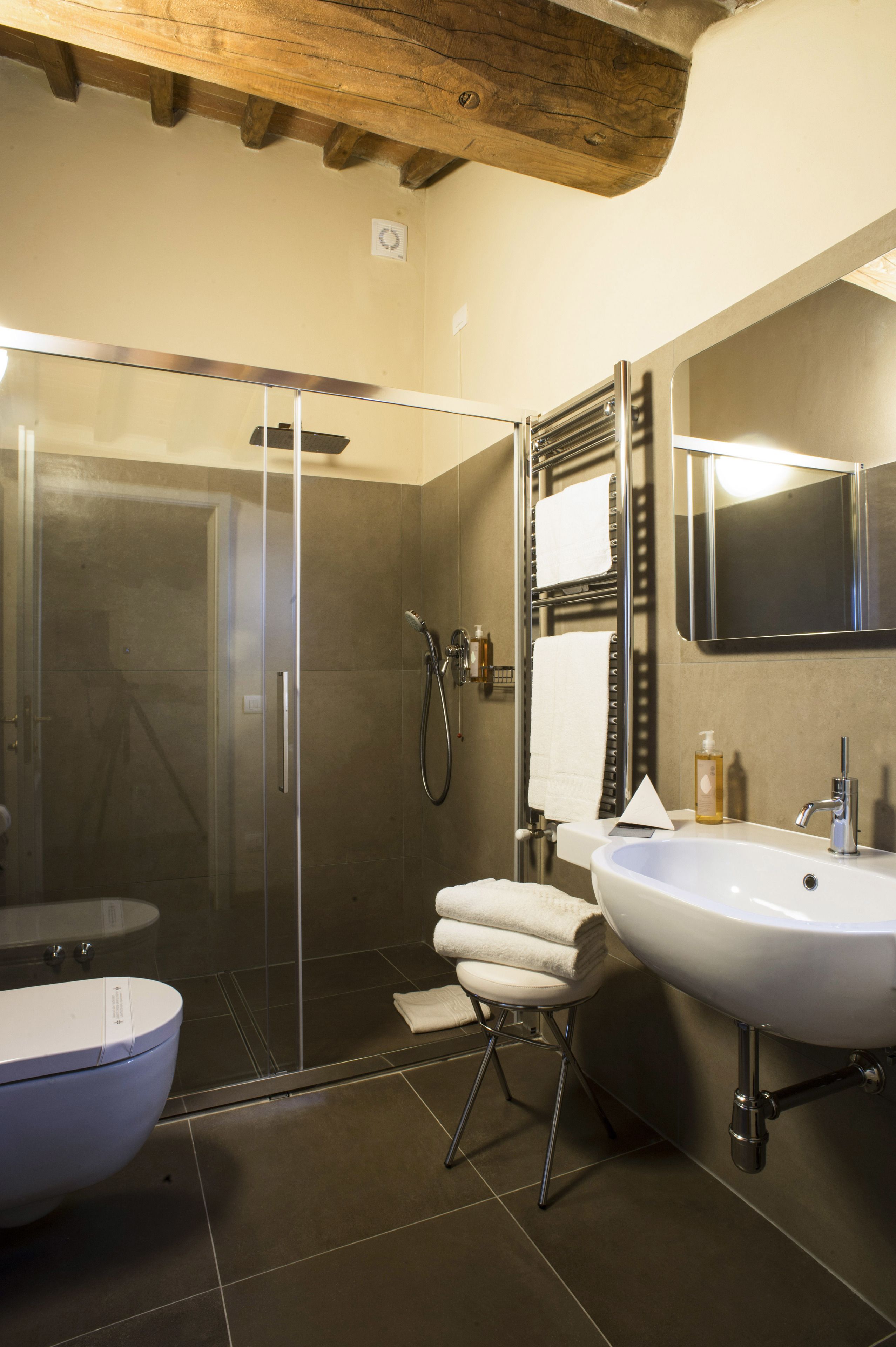 Un baño moderno con ducha envuelta en vidrio, un lavabo blanco y un espejo grande.