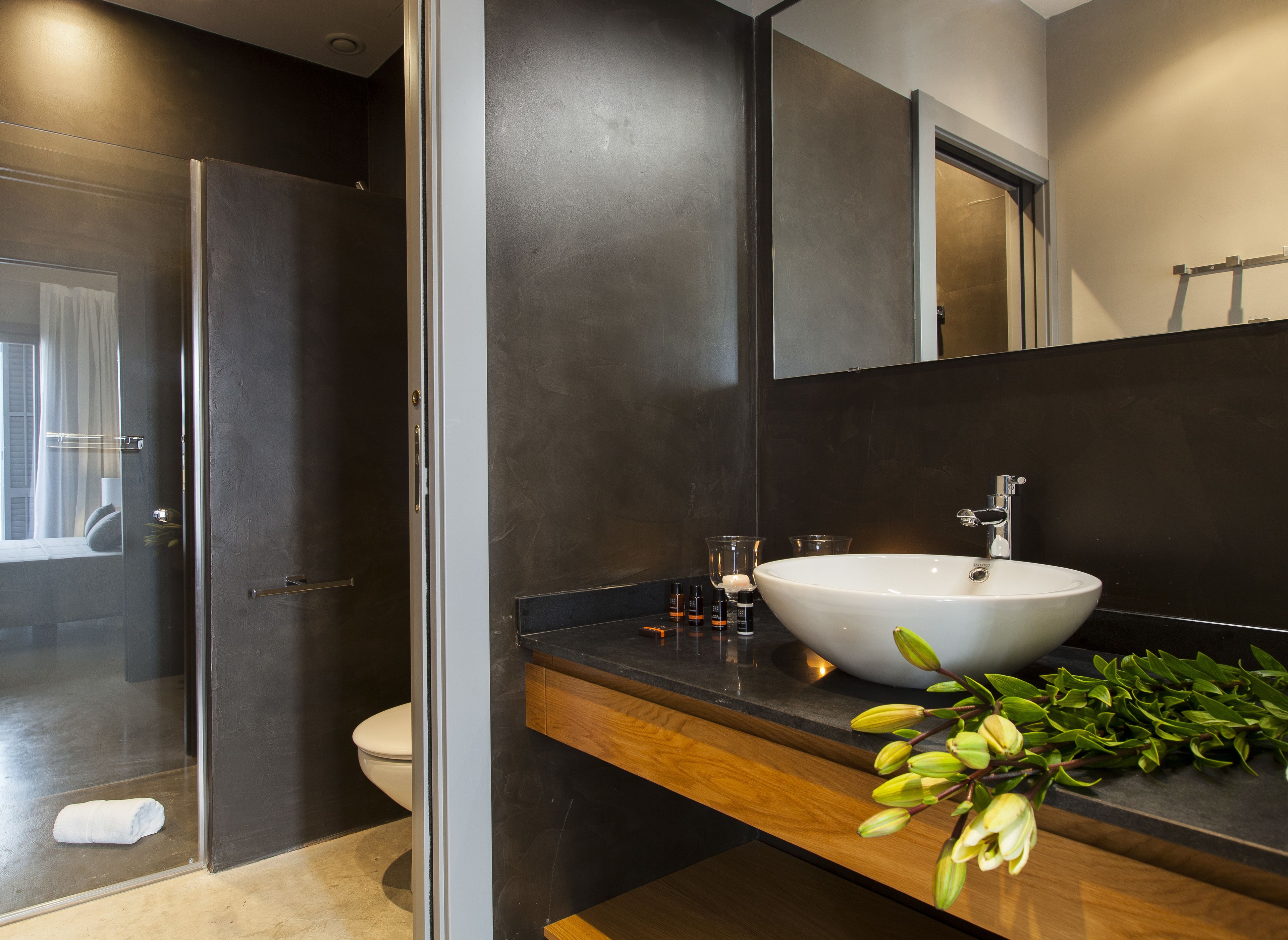 Ein modernes Badezimmer mit einem großen, weißen Waschbecken, dunklen Wänden und einer Duschkabine aus Glas.