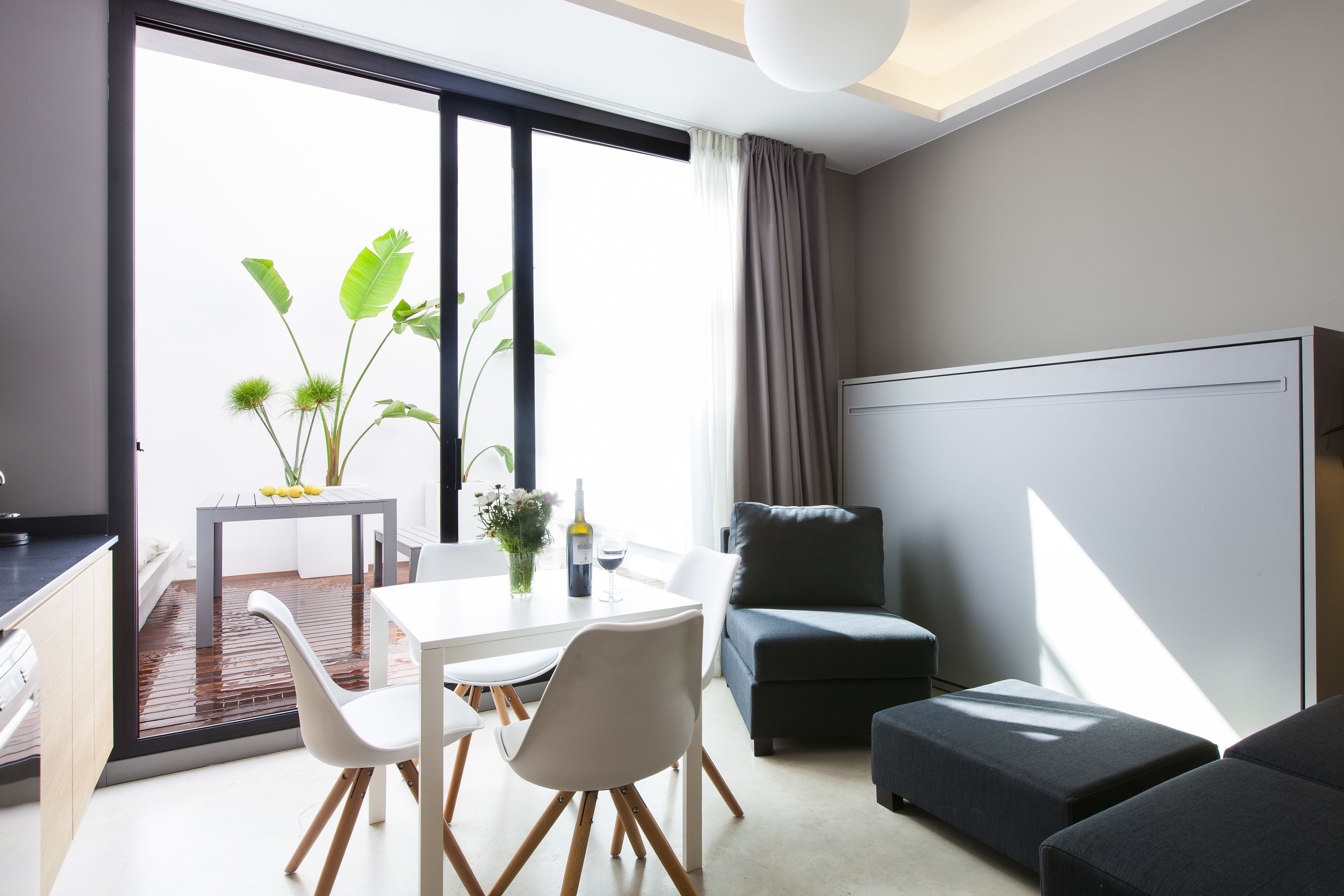 Una sala de estar moderna con comedor, un sofá y un ventanal con cortinas.