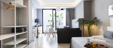 Une chambre d’hôtel moderne comprenant un lit, un coin repas, une kitchenette et un espace de vie.