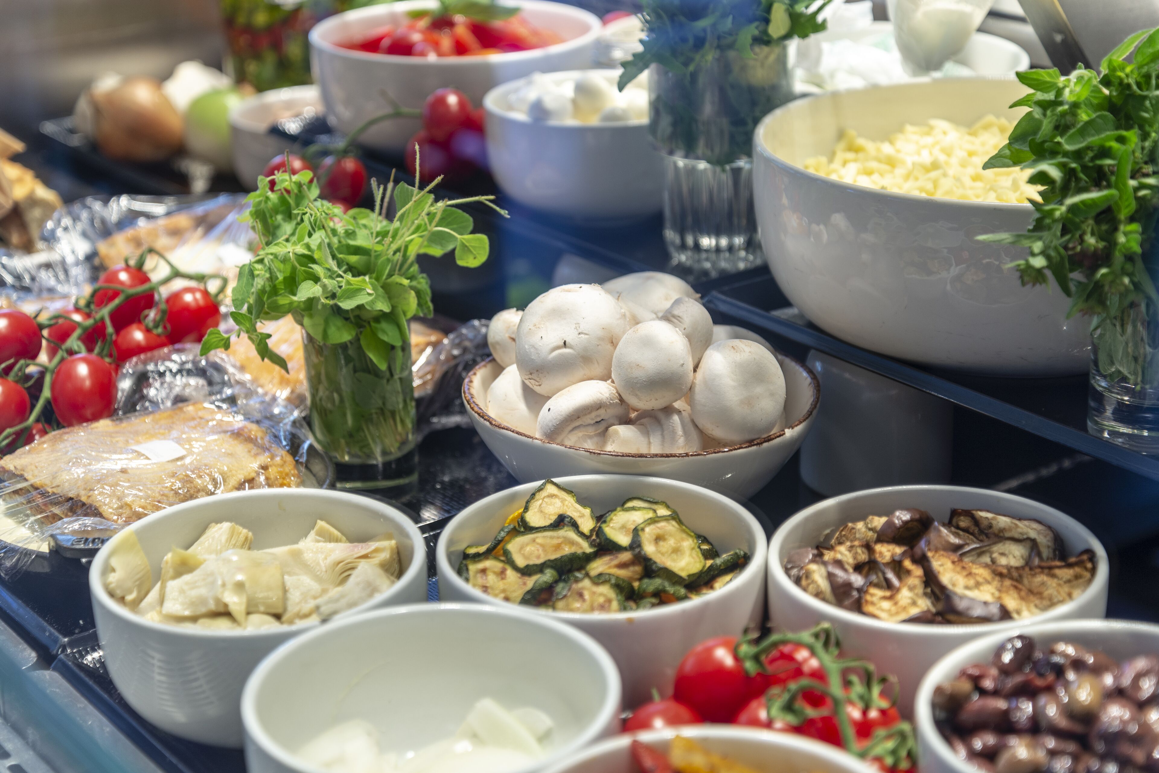 Un buffet proposant une variété d’aliments, notamment des légumes, du fromage et différents plats servis dans des bols.