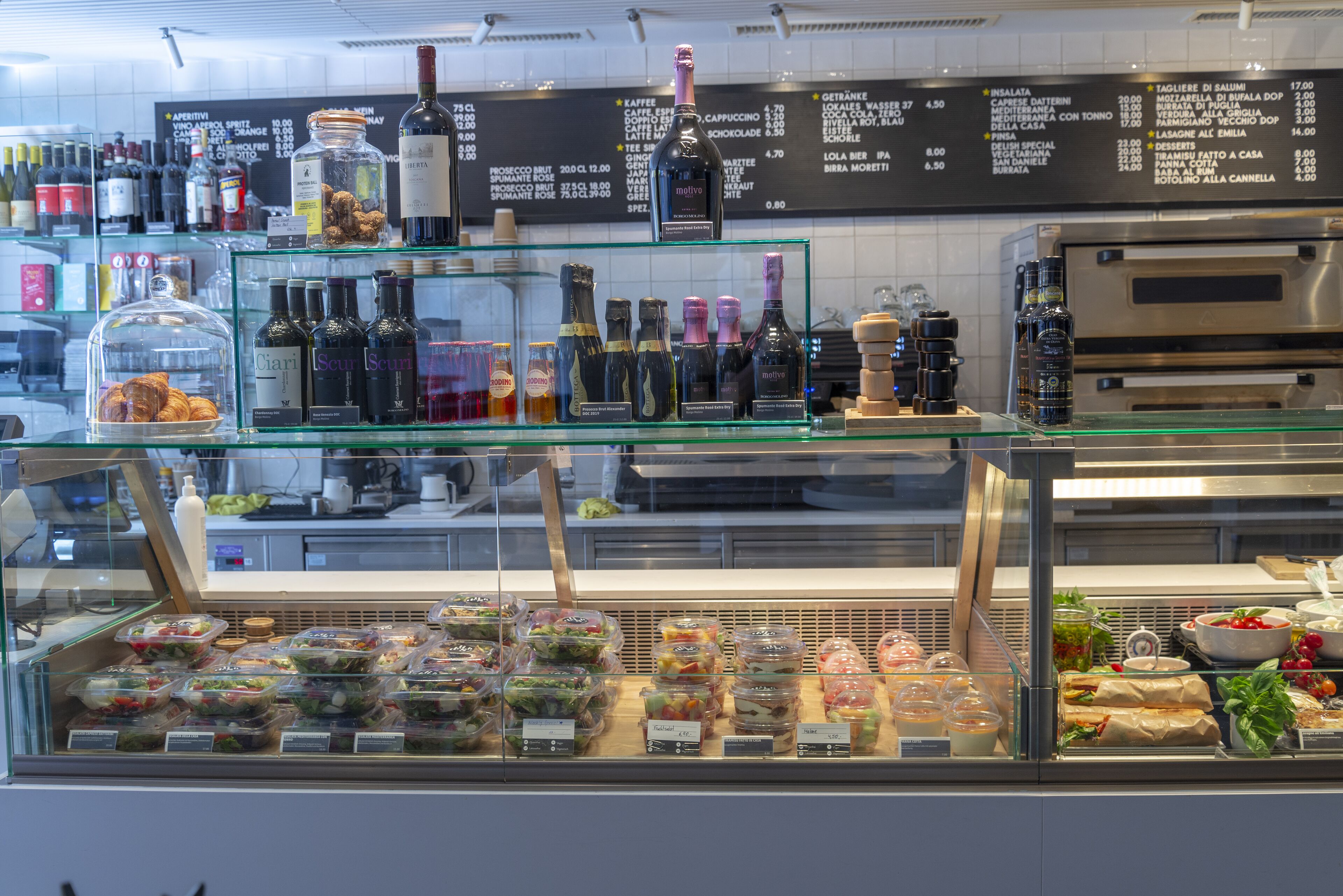 A deli counter with various food items and a wine selection.