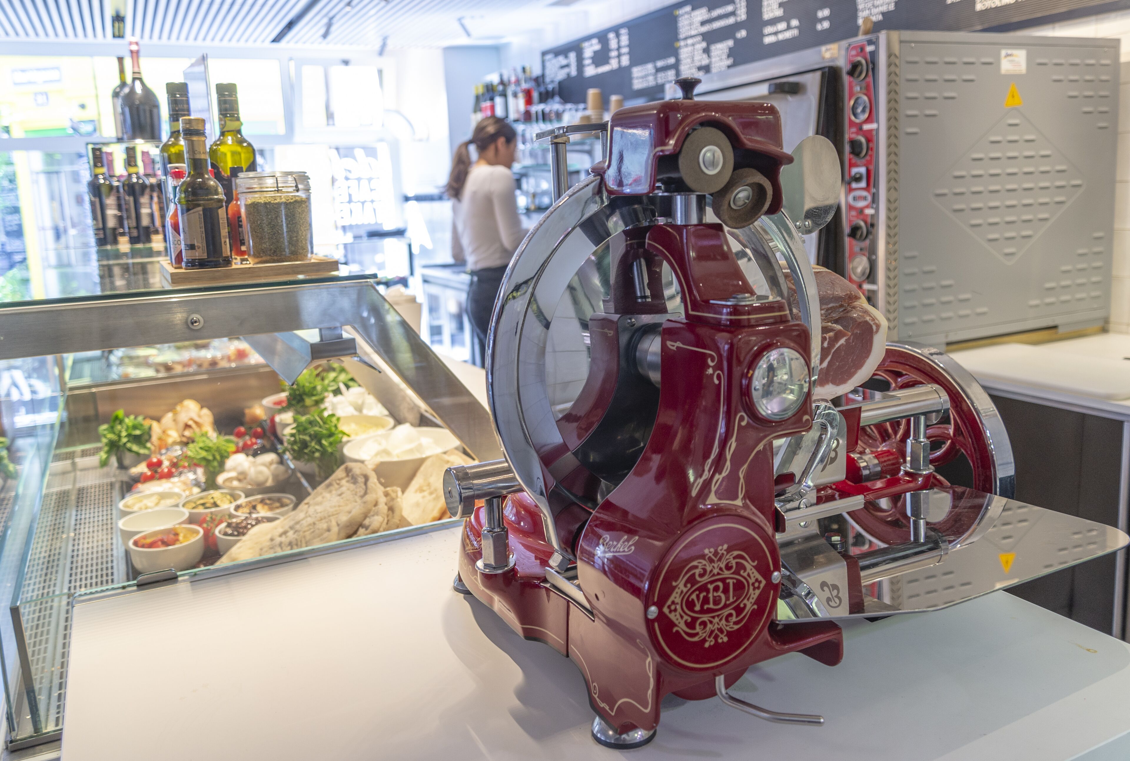 A vintage espresso machine with a glass display case containing various food items and condiments.