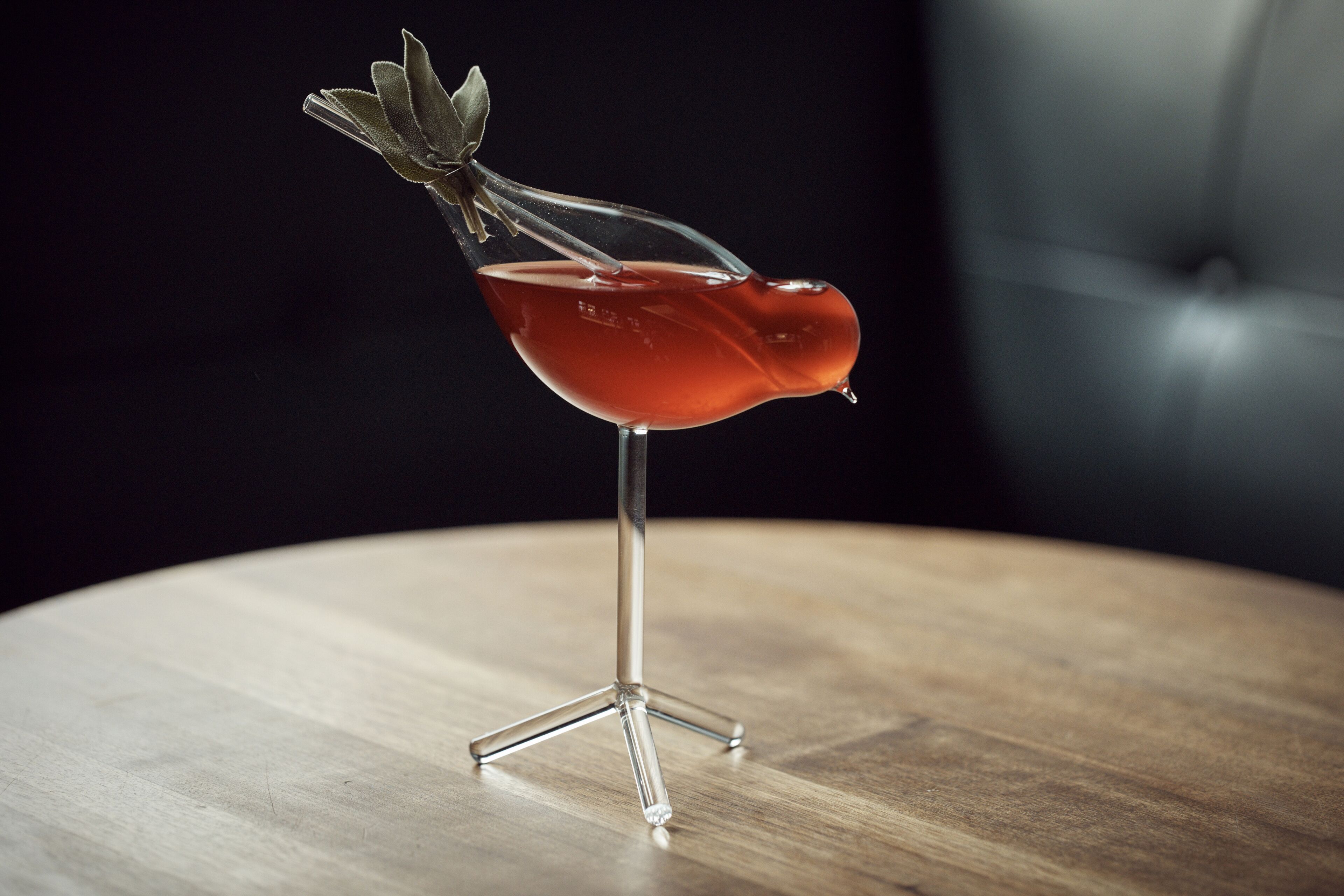 A cocktail in a unique glass on a wooden table.