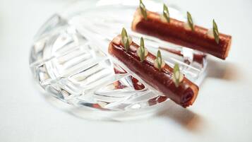 Une assiette en verre contenant deux brochettes de nourriture, chacune agrémentée d’une garniture verte.
