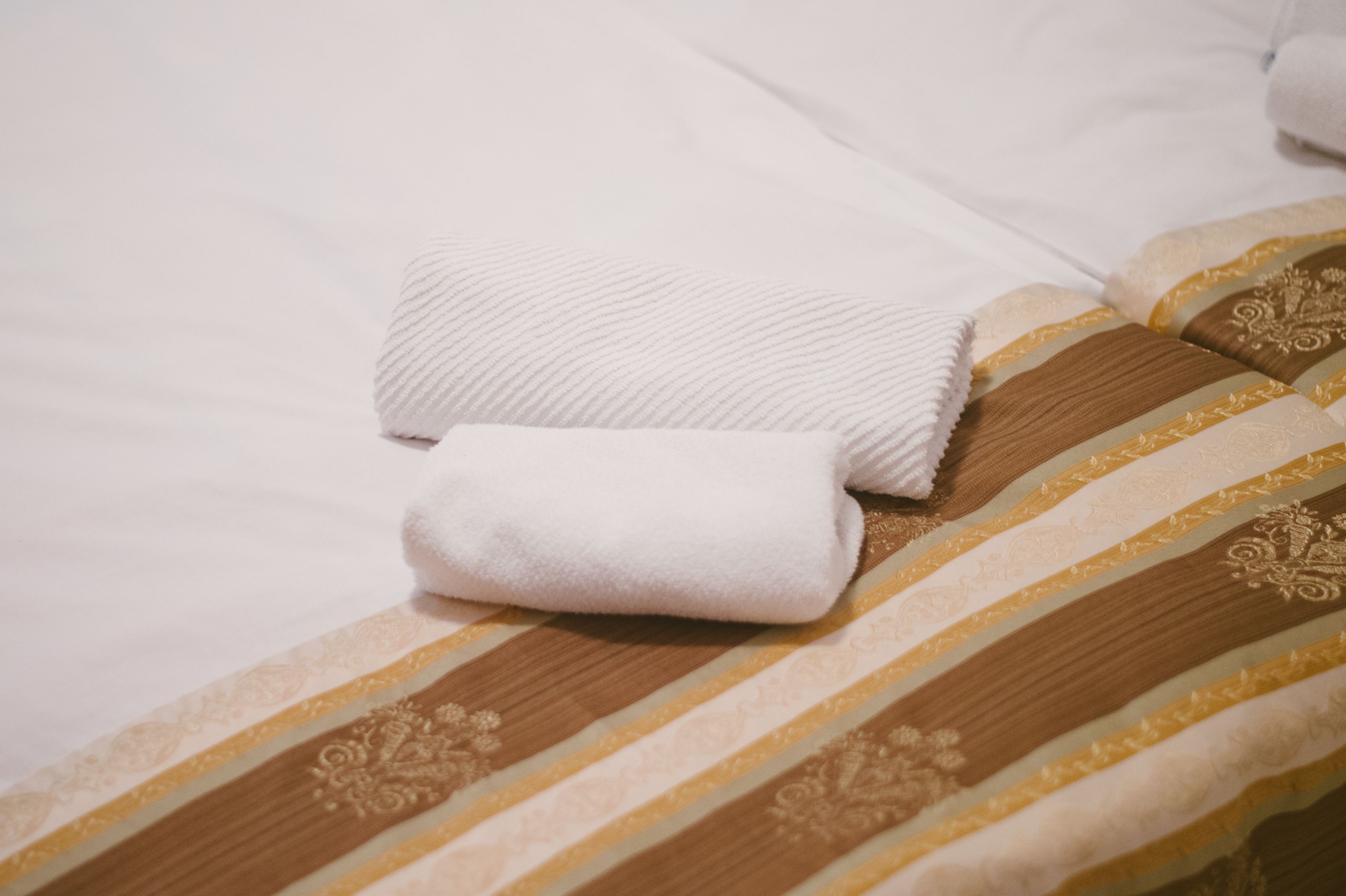A neatly made bed with striped bedding and a folded white towel.