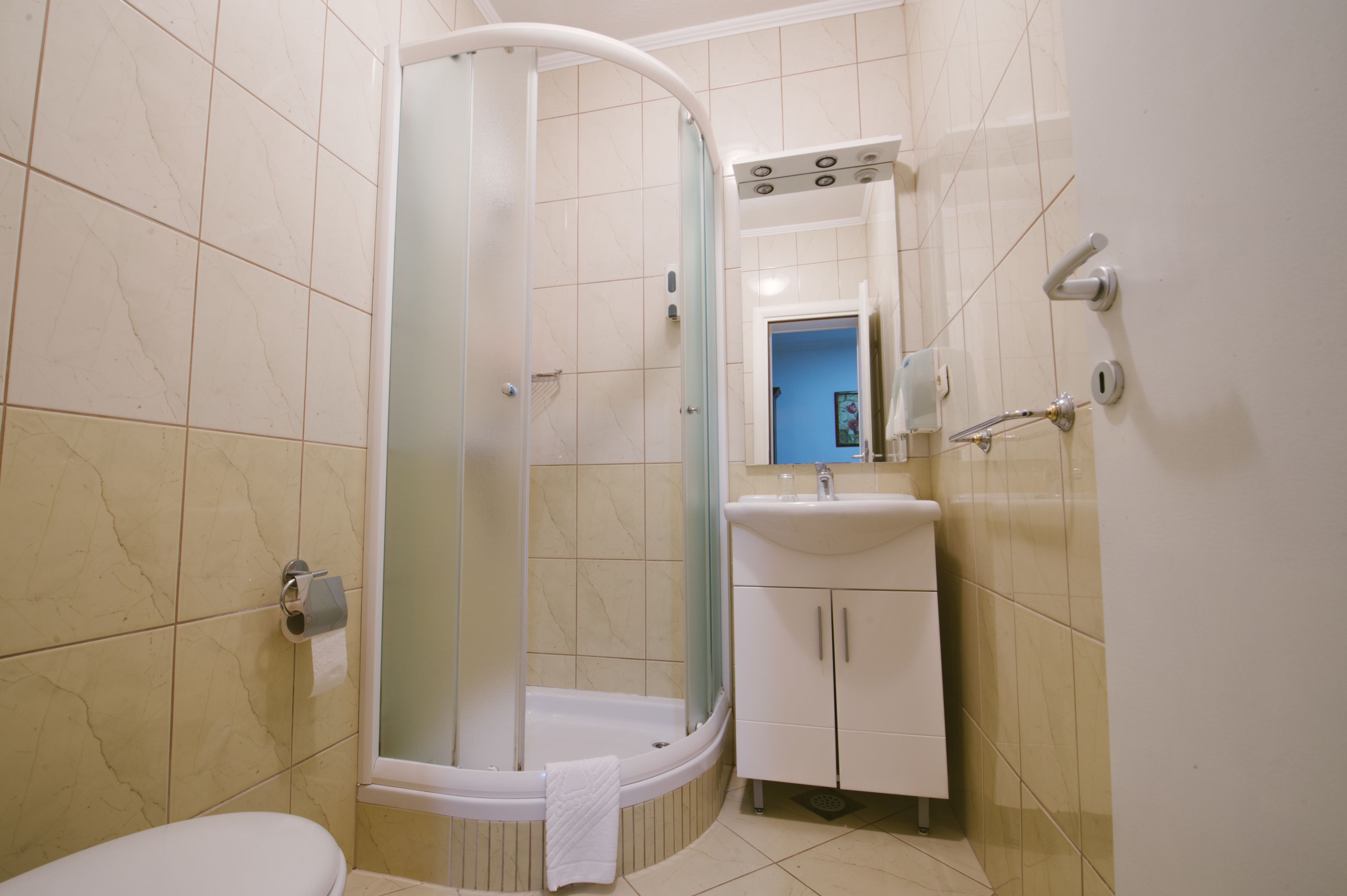 A bathroom with a shower, toilet, sink, and cabinet.