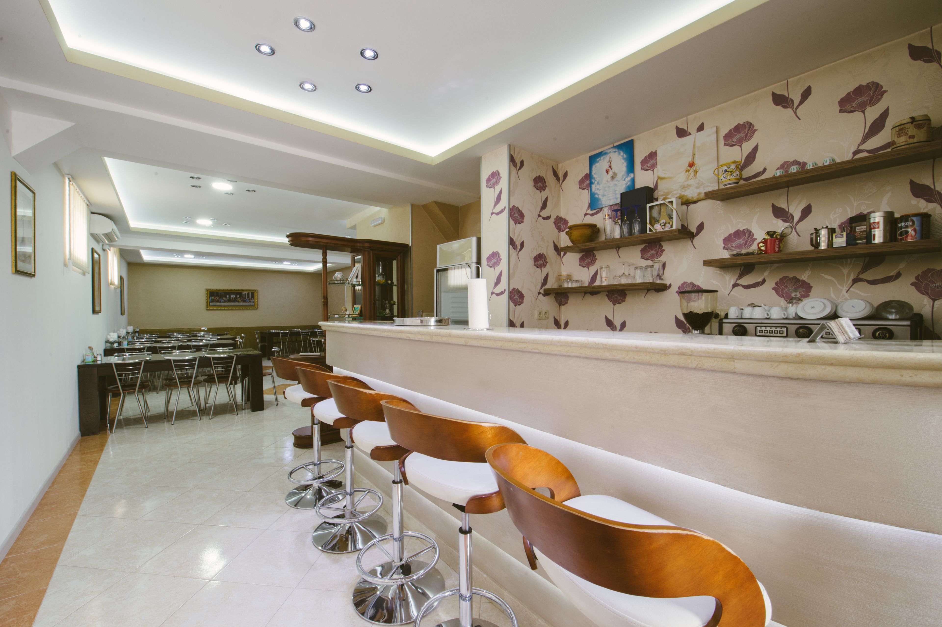A modern bar area with bar stools, a counter, and decorative shelves.