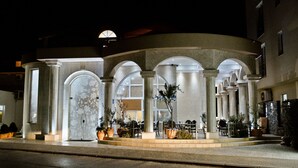 A hotel with a curved facade, large arched windows, and outdoor seating areas. - Hotel Flowers (Citluk)